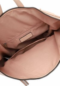 Interno rosa di una borsa con una tasca con zip e due scompartimenti aperti. Tessuto morbido con una leggera lucentezza. Finiture della zip in nero.