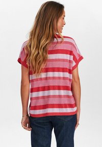 Röd och ljusrosa randig kortärmad skjorta med ribbat mönster, avslappnad passform och rund halsringning. Matchas med mörkblå jeans.