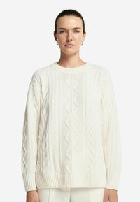 Flauschiger weißer Strickpullover mit Kabelmuster, geripptem Kragen und Bündchen sowie einem lässigen Oversize-Schnitt für zusätzlichen Komfort.