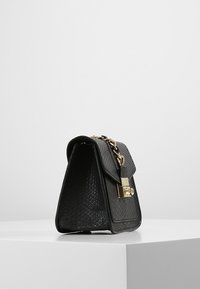 Czarna torebka z faux skóry w kształcie trójkąta, z złotym okuciem, łańcuszkowym paskiem oraz klapą. Teksturalna powierzchnia dodaje szczegółów.