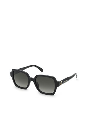 Lunettes de soleil à monture carrée noire avec verres dégradés foncés et détail doré subtil sur les branches, inclinées sur un fond blanc.