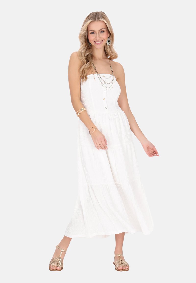 Weißes, trägerloses Maxikleid aus strukturiertem Stoff mit Knöpfen auf der Vorderseite und gestuftem Rock. Kombiniert mit goldenen Sandalen und geschichteten Halsketten.