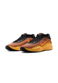 Nike løbesko med en sort og orange strikket overdel, teksturerede mønstre, gul sål og sort gummiydersål for godt greb.