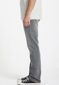 Gray denim jeans with a straight leg cut, worn with black sneakers. The fabric has a slight texture and a faded finish.