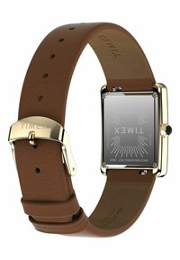 Montre avec bracelet en cuir marron, boîtier rectangulaire doré, dos en acier inoxydable et couronne noire, arborant des détails de marque gravés.