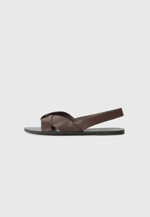 Brown leather sandals with a flat black sole, featuring cross-strap design and back strap for support. Smooth texture and minimal hardware.