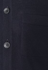 Mörk marinblå stickad kofta med två svarta fyrhålsknappar och en rektangulär patchficka på högra sidan.