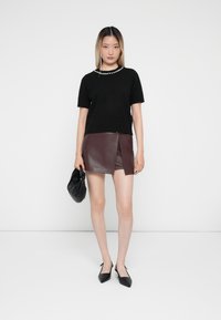 Black short-sleeve knit top with a pearl accent neckline; burgundy leather mini skirt with a front slit; black pointed-toe shoes; black handbag.