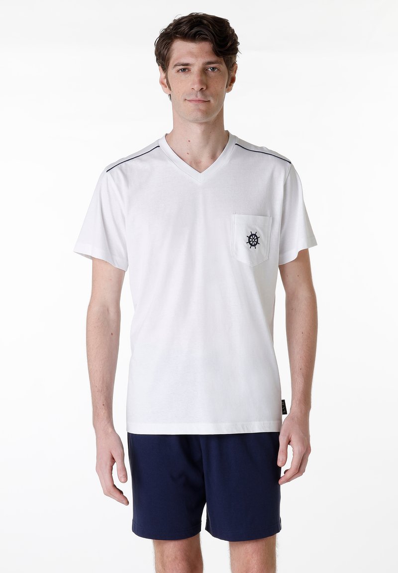 T-shirt bianco con scollo a V e tasca frontale, caratterizzato da un logo di timone blu navy. Include delicate righe blu navy sulle spalle.