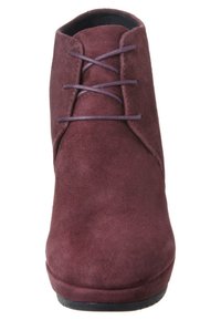 Botín de ante burdeos con punta redondeada y suela plana, que presenta cordones delgados y una textura suave. Diseño sencillo con detalles mínimos.