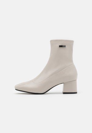 Beige LederStiefeletten mit spitzem Zeh, einem mittelhohen Blockabsatz und minimalen Nähdetails. Keine sichtbaren Beschläge oder Verzierungen.