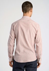 Camicia a maniche lunghe a righe in rosa chiaro e bianco, realizzata in tessuto morbido. Presenta un colletto a punta e polsini con bottoni, con orlo curvo nella parte inferiore.
