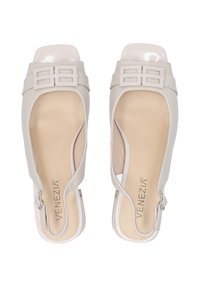 Beige slingback hakken met een vierkante neus, een bovenwerk van glad leer, een uitsnijd ontwerp, dubbele horizontale banden en een decoratieve gesp.