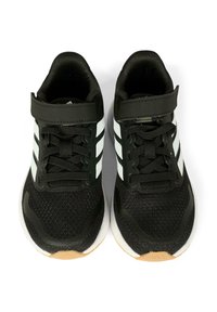 Zwarte sportschoenen van meshmateriaal, met witte strepen en een klittenbandsluiting. Ronde neus en rubberen zool met een gestructureerde grip.