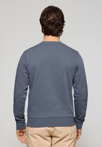 Grå sweatshirt med långa ärmar, rund hals, ribbade mudd och nederdel, tillverkad av mjukt tyg, utan synliga mönster eller detaljer.