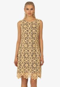 Spitzenkleid mit floralen Ausschnitten, beiger Farbe, ärmellosem Design, komplexem Muster und gewelltem Saum.