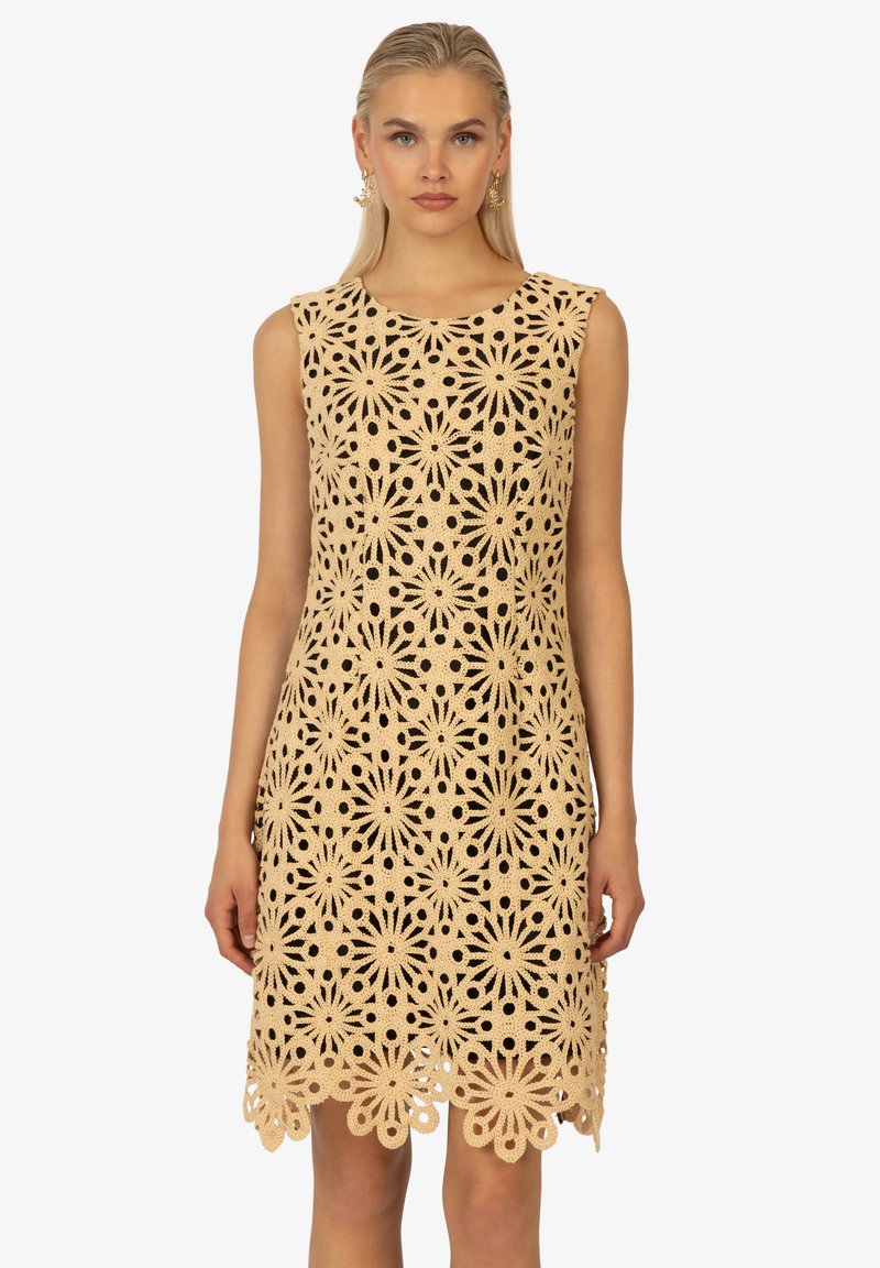 Spitzenkleid mit floralen Ausschnitten, beiger Farbe, ärmellosem Design, komplexem Muster und gewelltem Saum.