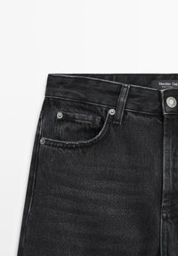 Jeans in denim nero con vita alta, dotati di una tasca anteriore, accessori in metallo e dettagli di cucitura discreti. L'etichetta riporta "Massimo Dutti."