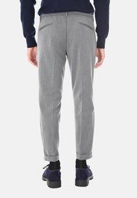 Pantaloni grigi con una texture sottile, dotati di due tasche posteriori e orli arrotolati. Abbinati a scarpe in suede viola.