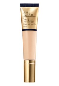 Beige putkiloon Estee Lauder Futurist Hydra Rescue Moisturizing Makeup. Kullan aksentit, laivastonsiniset korkki ja SPF 45 -merkintä. Sujuva rakenne näkyvissä.