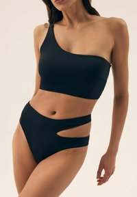 Czarny zestaw kąpielowy składający się z topu na jedno ramię oraz majtek z wysokim stanem z wycięciami. Gładki, elastyczny materiał i minimalistyczny design.