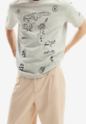 T-shirt en coton gris avec diverses illustrations brodées, comprenant des personnages et des formes géométriques, en fil bleu foncé.