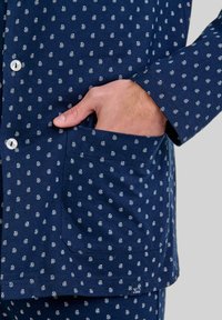 Conjunto de pijama de estampado marino en tela suave, con pequeños diseños blancos en espiral, cierre de botones y un bolsillo lateral en la parte superior.