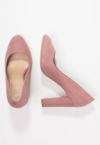 Růžové semišové lodičky na vysokém podpatku se čtvercovým podpatkem, zaoblenou špičkou a hladkým povrchem, s výřezem po stranách.