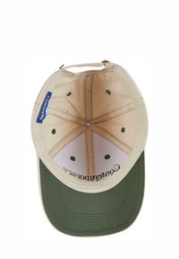 Beige stofkasket med en grøn skygge og inderside, der har syninger, ventilationshuller og et logo-label på siden.