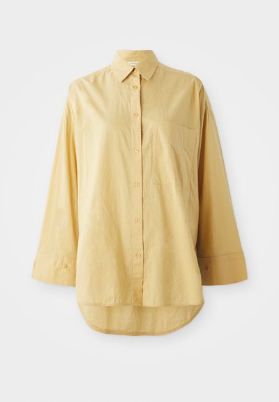 Yellow button-up shirt with a pocket, long sleeves, and a rounded hem. Made of lightweight, textured fabric. Features orange buttons.