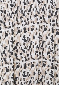 Tessuto con stampa animale caratterizzato da una combinazione di colori beige, nero e bianco, con un design testurizzato e plissettato in tutto il tessuto.