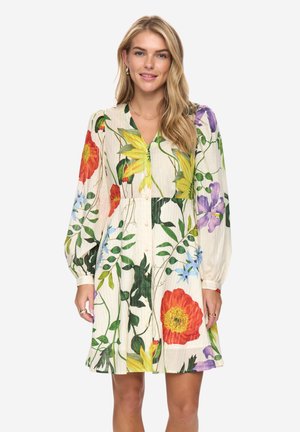 Mujer vistiendo un vestido hasta la rodilla, de manga larga, con grandes estampados florales de colores, con botones al frente y escote en V.