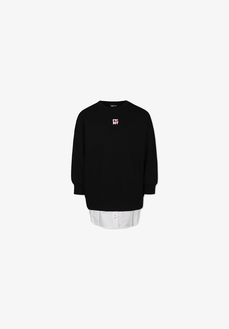 Felpa nera con collo rotondo, con un piccolo logo rosso e bianco sul petto. Indossata sopra una camicia bianca con un orlo visibile.