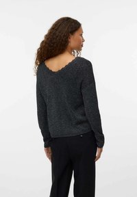 Suéter de punto negro y plateado con escote trasero en forma de concha, corte relajado, mangas largas y patrón texturizado.
