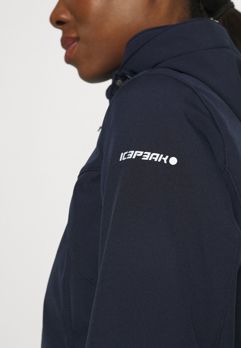 Veste bleu marine au toucher lisse, arborant un logo "ICEPEAK" blanc bien visible sur la manche et une fermeture éclair sur le devant.
