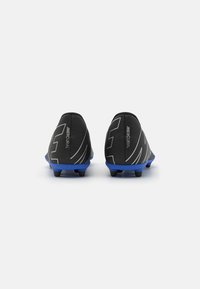 Botas de fútbol negras con suelas azules, con una parte superior lisa, diseños angulares y acentos texturizados en el talón. Los tacos para tracción son visibles.