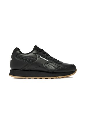 Sort Reebok lædersneaker med sort sål og tan gummi ydersål, synligt logo på siden, snøredesign og lav profil.