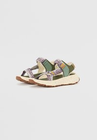 Sport sandals featuring a green and cream design, with purple patterned straps, adjustable closures, and a speckled beige rubber sole.
