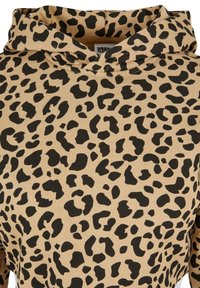 Sweat à capuche beige avec motif de taches léopard noires irrégulières et étiquette intérieure visible à l'encolure.