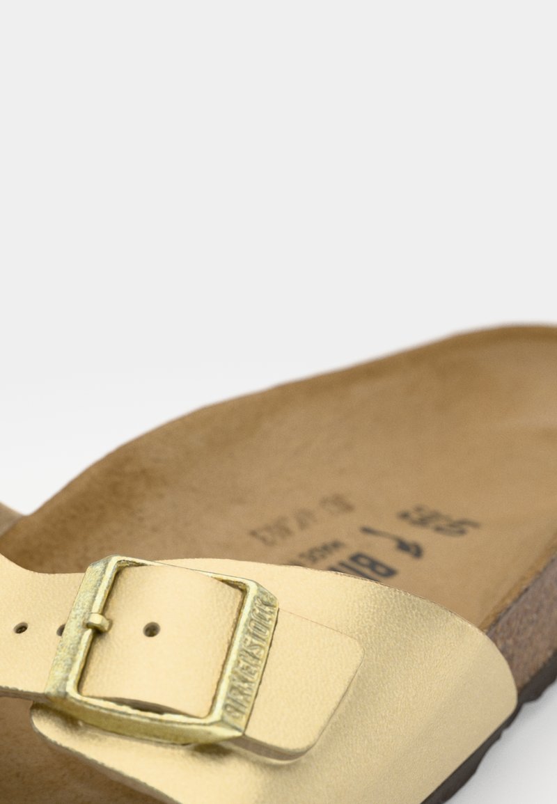 Gelbe Leder-Sandale mit einer goldenen Schnalle, konturiertem Fußbett und braunem Wildleder-Futter. Das Design ist minimalistisch und ohne Muster.