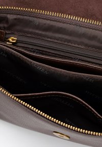 Hnědá peněženka na zip s několika přihrádkami. Texturovaný povrch, zlaté kování a tmavý vnitřek s potiskem značky.