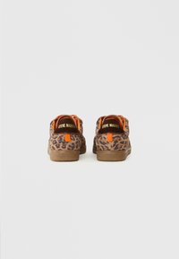 Tênis de estampa de leopardo com parte superior texturizada em marrom, detalhes em laranja e um logotipo no calcanhar. Sola de borracha e design da biqueira arredondada.