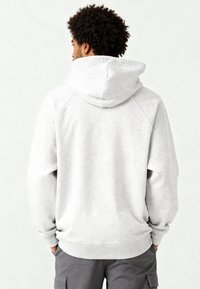 Felpa grigia chiaro con cappuccio ampio e strutturato, maniche raglan e polsini a coste. Realizzata in tessuto morbido con una consistenza liscia.