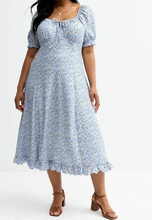 Jasnoniebieska sukienka w kwiaty z bufkami na rękawach, kwadratowym dekoltem i falbankowanym dołem. Na delikatnym materiale znajdują się małe żółte i białe kwiaty.