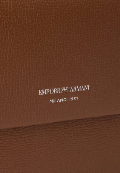 Καφέ υφασμάτινη επιφάνεια από δέρμα με λευκό λογότυπο και κείμενο Emporio Armani ανάγλυφα.