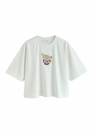 White cropped t-shirt with subtle stripes and embroidered stacked teacups, featuring green, pink, and navy colors with floral and polka dot details.