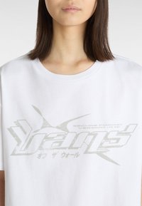 Hvid bomulds t-shirt med en stor, falmet grå grafikprint med tekst og abstrakte former på forsiden. Rundet halsudskæring, korte ærmer.