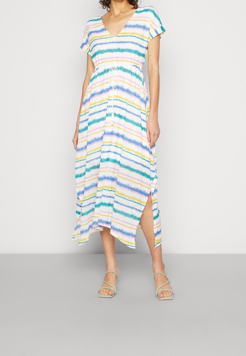 Femme portant une robe midi rayée colorée avec un col en V, des manches courtes, une taille resserrée par un cordon et des fentes sur les côtés, associée à des sandales à brides vert clair.