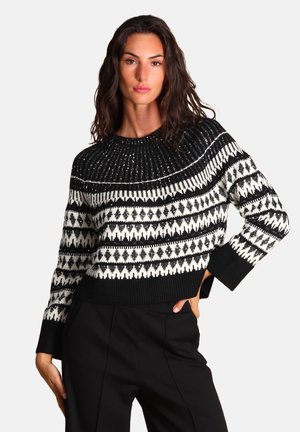 Maglione lavorato a maglia bianco e nero con collo rotondo, caratterizzato da motivi geometrici e orlo a coste, texture con una finitura leggermente lucida.
