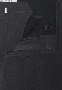 Zwarte stoffen broek met een rits aan de voorkant, knoopsluiting en binnenzak. Kenmerkt zich door een gladde textuur en subtiele stikseldetails.